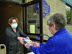 The Nanton Thelma Fanning Library is offering a curbside pickup service Tuesdays to Fridays, from 11 a.m. to 3 p.m., and plans to reopen on July 7. Here, employee Marlene Doyle hands some books to manager Gloria McGowan.