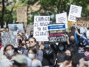 People hold up signs during a demonstration calling for justice for the death of George Floyd and victims of police brutality, in Montreal, Sunday, June 7, 2020. 
THE CANADIAN PRESS/Graham Hughes