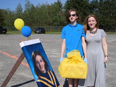 Graduating student Matthew Thompkins and his mom, Andrea, pose for a picture near Matthew's photo at St. Anne Catholic School's Grade 8 drive-thru graduation ceremony in Hanmer, Ont. on Wednesday June 17, 2020. More than 50 graduating students and their families took part in the ceremony. John Lappa/Sudbury Star/Postmedia Network