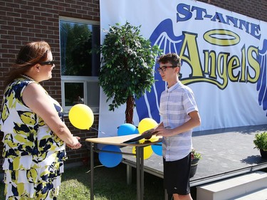 Quintin Martel, 13, is congratulated by principal Laura Stirrett at St. Anne Catholic School's Grade 8 drive-thru graduation ceremony in Hanmer, Ont. on Wednesday June 17, 2020. More than 50 graduating students and their families took part in the ceremony. John Lappa/Sudbury Star/Postmedia Network