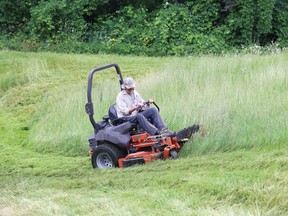 A staff member with the City of Greater Sudbury Parks Services Department cuts thick, tall grass on a hill at Bell Park on Tuesday.