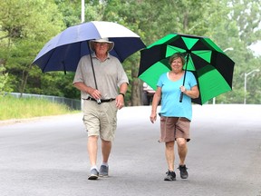 Al Cruthers and his wife, Linda, go for a walk while attempting to keep dry in Copper Cliff, Ont. on Tuesday June 23, 2020.