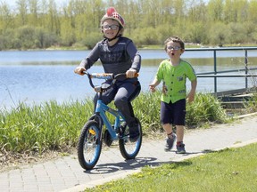 Asher Steudle, 7, is seen here riding his bicycle at Porcupine Lake with his brother Link, 5, chasing after him during what was a warm, sunny day in Timmins on Monday. Environment Canada's forecast for Timmins calls for two days of cloudy conditions and sporadic rainfall before the sunshine is expected to make its return Thursday.

RICHA BHOSALE/The Daily Press