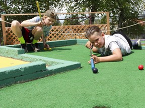 Jackson Duclos, 9, right, got creative while trying to sink a ball at the Mini Putt/Batting Cages in Hollinger Park Tuesday, using his club as a pool cue while his friend Henry Klooster, 10, looks on. They were enjoying a hot, sunny day outdoors and it's going to be even hotter Wednesday -- to the point where Environment Canada has issued an extreme heat warning with the daytime temperature expected to reach a high of 34 C.

RICHA BHOSALE/The Daily Press
