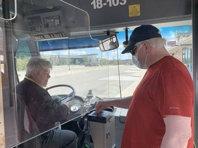 Timmins Transit dispatcher Marlice MacLeod looks on as city resident Allen Kyle boards the bus at the station downtown and demonstrates how riders will resume paying fares starting this Sunday. Kyle was boarding the bus while on his way to pick up his weekly groceries Thursday afternoon.

ELENA DE LUIGI/The Daily Press