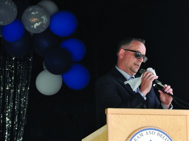 County Central High School vice-principal Don Monts cleans the microphone between speeches Saturday during the school's 2020 graduation ceremony, which was held outside the Cultural-Recreational Centre (CRC) due to COVID-19 gathering restrictions. A stage was set up by the doors to the CRC, and the graduates and their families listened to the speeches from their vehicles.