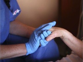 A nurs wearing protective gloves holds the hand of a patient in the palliative care unit of the the Eugenie Hospital in Ajaccio, on the French Mediterranean island of Corsica, on April 23, 2020, on the thirty-eighth day of a lockdown in France aimed at curbing the spread of the COVID-19 disease, caused by the novel coronavirus. - A message, a drawing or a picture slipped into the coffin, letters from caretakers to the families... Several "rituals" have been established in Corsica to deal with the deaths of COVID-19 patients deprived of their families, doctors told AFP. (Photo by Pascal POCHARD-CASABIANCA / AFP) (Photo by PASCAL POCHARD-CASABIANCA/AFP via Getty Images)