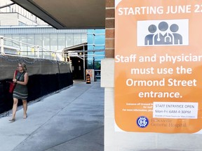 Laurie Ouellette, an employee at Brockville General Hospital, uses the main entrance on Monday afternoon, as a sign explains the latest access rules. She was using the main entrance after the staff entrance on Ormond Street was closed. (RONALD ZAJAC/The Recorder and Times)