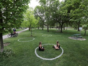 Women sit in a field where circles were painted to help visitors maintain social distancing to slow the spread of the coronavirus disease (COVID-19) at Trinity Bellwoods park in Toronto, Ontario, Canada May 28, 2020. REUTERS/Chris Helgren