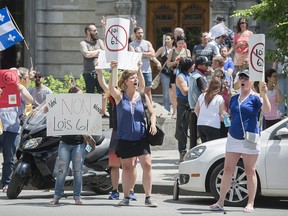 People hold up signs opposing Bill 61 outside Quebec Premier Francois Legault's office in Montreal, Saturday, June 6, 2020, as the COVID-19 pandemic continues in Canada and around the world. THE CANADIAN PRESS/Graham Hughes