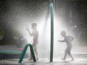 Mya Boldt, 6, and little brother Kaius, 4, stroll through a sprinkler in the Gibbons Park splash pad late Tuesday afternoon on August 20, 2019. Mike Hensen/The London Free Press