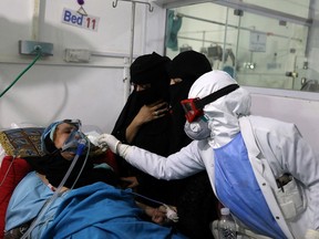 Women watch as a nurse tends to their relative who is being treated at an intensive care unit of a hospital for the coronavirus disease (COVID-19) in Sanaa, Yemen, on Thursday (Khaled Abdullah/Reuters)