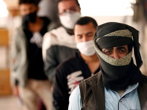 People stand in line to receive vouchers at a food distribution centre supported by the World Food Programme in Sanaa, Yemen, on June 3. (Khaled Abdullah/Reuters)