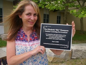 Southwold Public School parent Biz Thompson holds the plaque which dedicates the outdoor education area behind her, in her honour.