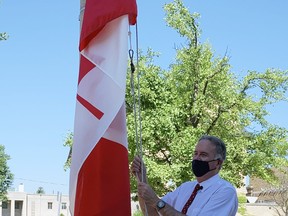 Mayor Kevin Davis raises a new Canadian flag at a ceremony at city hall in celebration of Canada's 153rd birthday on Wednesday. The event included the singing of O Canada by Jennifer Page and an appearance by town crier David McKee.