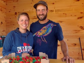 Cassie Ryan and Ryan Whitehead, owners of Twin Rivers Farm, with a flat of fresh-picked strawberries. The couple, in their second year in business, are working within new regulations set by the Berry Growers of Ontario. Please see A5 for story on how farmers' market in Desbarats is dealing with pandemic. ELIZABETH CREITH