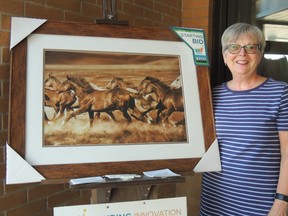 Auxiliary Co-President Pat Emmerton stands with the latest print, entitled "Unbroken".