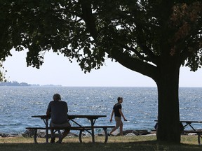 A man enjoys some time in the shade under a tree in MacDonald Park on the waterfront across from Kingston General Hospital. (Ian MacAlpine/The Whig-Standard)