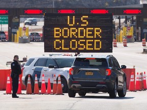 In this file photo, U.S. customs officers speak with people in a car beside a sign saying that the U.S. border was closed at the crossing near Lansdowne on March 22. (Lars Hagberg/Getty Images)