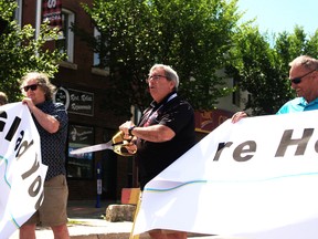 Mayor Dan Reynard, centre, on Main Street in downtown Kenora cutting the "ribbon" - a banner that reads 'Welcome! Glad You Are Here' - on Wednesday, July 15. This ceremony marked the "reopening" of many places in Kenora as the province is set to move into Stage 3 of their COVID-19 pandemic reopening plan this Friday.