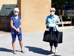 Diane Bergeron and Linda Fredette are Meals on Wheels volunteers in Elliot Lake. They both drive on Thursdays. Fredette received a tote bag containing the meals she is to deliver, while Bergeron waits for her tote bag. KEVIN McSHEFFREY/THE STANDARD