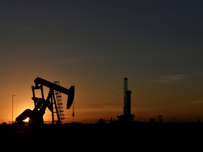 A pump jack operates in front of a drilling rig at sunset in an oil field in Midland, Texas. (Nick Oxford/Reuters)