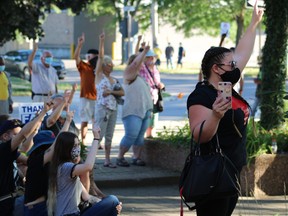 The crowd at the Anti-Racism Against Migrant Workers rally on Friday took a moment to salute the migrant workers that make sacrifices for Ontario farms. At right is immigration consultant Nancy Thompson. (ASHLEY TAYLOR)