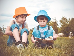 Two boys read in a field. The Spruce Grove and Stony Plain Public Libraries are still doing their normal summer reading programs during the COVID-19 pandemic.