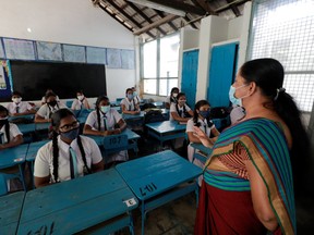 Students wearing protective face masks practice keeping a one meter distance while listening to their class teacher on the first day at Vidyakara college, which re-opened after almost two months of lock-down amidst concerns about the spread of coronavirus disease (COVID-19), in Colombo, Sri Lanka, July 6, 2020. REUTERS/Dinuka Liyanawatte