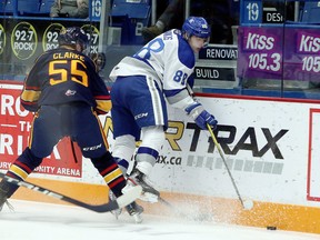 Sudbury Wolves forward Kosta Manikis (88) protects the puck as he takes a hit from Barrie Colts defenceman Brandt Clarke (55) during first-period OHL action at Sudbury Community Arena in Sudbury, Ontario on Friday, October 18, 2019.