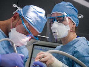 Dentist Fiez Mughal (L) and Dental Nurse Johanna Bartha (R) carry out a procedure on a patient in one of the six surgery rooms at East Village dental practice on May 28, 2020 in London, England. They are wearing PPE similar to what Ontario dental clinics have had to start wearing to begin accepting patients as they reopen.