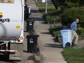 A resident collects his garbage and recycling bins in Fort McMurray, Alta., on Thursday June 2, 2016. Ian Kucerak/Postmedia Network