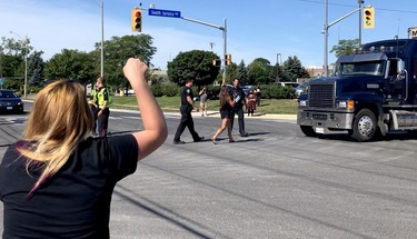 Ag supporters, left, shout at police to remove activist Sabrina Desgagnes as she walks into the intersection in front of a moving transport attempting to entering the Sofina Fearman's Pork Ltd. processing plant in Burlington on a green light and right-of-way, July 30, 2020. (Diana Martin, Ontario Farmer)