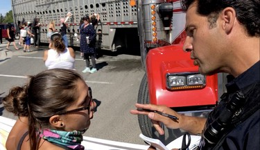 Halton Regional police, right, and activist Sabrina Desgagnes, left, argue over what the time delay is for trucks (Diana Martin, Ontario Farmer)