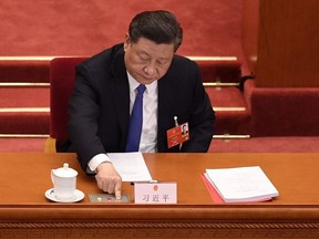 This file photo taken on May 28, 2020 shows China's President Xi Jinping voting on a proposal to draft a security law on Hong Kong during the closing session of the National People's Congress at the Great Hall of the People in Beijing. - China passed a sweeping national security law for Hong Kong on June 30, 2020, a historic move that critics and many western governments fear will smother the finance hub's freedoms and hollow out its autonomy. (Photo by NICOLAS ASFOURI / AFP)