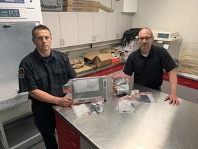 Const. Damian Muchowski (left) and Det. Derek Butler display examples of electronic devices seized by the Brantford police internet child exploitation unit.