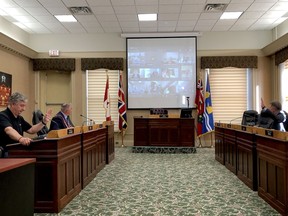 For the first time since the COVID-19 shutdown, a third of Brockville council was in the main council chamber for a regular meeting on Tuesday. From left are Coun. Mike Kalivas, Mayor Jason Baker and Coun. Larry Journal, while other councillors and staff appear via teleconference on the large screen. (RONALD ZAJAC/The Recorder and Times)