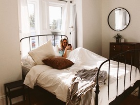 Alex Abrams poses with a cup of coffee in bed in this bedroom at Samantha Pike's Airbnb in Gananoque. Submitted photo