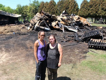 Lauren Edwards, left, founder of Charlotte's Freedom Farm, and Christine Rettig, who rescued 35 animals, stand in front of a barn that was destroyed in a fire at the Brook Line facility near Chatham, Ont. just before midnight Wednesday. Ellwood Shreve/Chatham Daily News/Postmedia Network