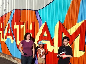 Chatham artist Rose Butler, 23, left, is working with two of her students, Riya Deo, 11, and Emmett Sherbourne, 14, to create this mural located on the side of Augie's Barber Shop on St. Clair Street in Chatham. Ellwood Shreve/Chatham Daily News/Postmedia Network