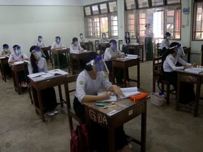 Students wearing masks and face shields attend classes with social distance measure during the first day of reopening of public high schools following closure due to the COVID-19 coronavirus in Yangon in Myanmar on July 21, 2020. (Photo by Sai Aung Main / AFP)