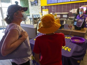 Maureen Campbell and her son Benjamin Daabous, 12, order drinks at Booster Juice on Wonderland Road with manager Valerie Balcarras behind the till. Alll are wearing medical masks to slow COVID-19's spread. Photograph taken on Thursday July 2, 2020. (Mike Hensen/The London Free Press)