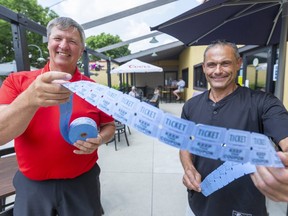 Barry Travnicek, who volunteers for the MS Society, holds up a roll of 50/50 tickets with Eastside Bar & Grill owner George Karigan. Twelve years of 50/50 draws, with $1 tickets, has raised $500,000 for the charity. (Mike Hensen/The London Free Press)