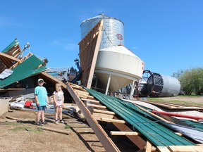 Ava Edwards, age 10, and her sister Ellie, age seven, look at the remains of their parents' seed cleaning plant in the Arborfield area. Strong winds and hail wreaked havoc in the northeast in a very fast storm on July 2. Photo Susan McNeil.