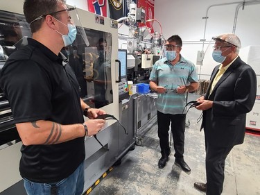 MPP Vic Fedeli (right), Ontario's Minister of Economic Development, Job Creation and Trade, watches as the headpieces for the face shields being made by Pembroke's SRB Technologies during a tour of the facility on July 20. Looking on are Bennett Robinson (left) who was running the machine and company vice-president Ross Fitzpatrick.