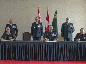 The outgoing Commander 4th Canadian Division Support Group (4 CDSG), Brig.-Gen. Louis Lapointe (left) signs over authority of 4 CDSG to the incoming 4 CDSG commander, Col. John Vass, with the 4th Canadian Division, commander Brig.-Gen. Conrad Mialkowski (centre) presiding over during the first ever virtual Change of Command and Change of Appointment ceremony at Garrison Petawawa. The ceremony which was held at the Normandy Officers Mess Friday June 26, 2020, was attended by only a handful of guests to respect COVID-19 precautions and was live-streamed on the Garrison Petawawa Facebook page. Able Seaman Elizabeth Ross