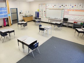An empty classroom with intentionally-spaced desks awaits returning students.