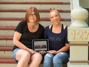 Rhonda Melanson, left, and Lois Nantais sit on the steps of the Lawrence House Centre for the Arts holding an iPad displaying the the site for Uproar, a new literary blog via the Lawrence House. Members of the non-profit's literary committee, including Melanson and Nantais, are behind the new community space for writers. (Photo by N. Leonard Segall)