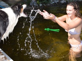 Emma Micieli of Markham plays with Jackson the mini Aussie shepherd at her family's cottage on Panache Lake on Thursday. The weather this weekend will be hot again, with partly cloudy skies.