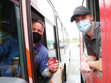 Ron Duchesne, left, a transit driver with the City of Greater Sudbury, collects his order from Connor McNally at a Tim Hortons drive-thru trailer at the City of Greater Sudbury's facility on Lorne Street in Sudbury, Ont. on Thursday July 16, 2020. Tim Hortons set up the trailer as a way of giving back to Sudbury GOVA transit employees "who have been working tirelessly throughout the pandemic to make sure other essential workers and residents are able to get around their city," said a release from Tim Hortons. John Lappa/Sudbury Star/Postmedia Network